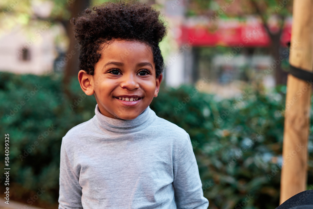 Happy brunette little boy in an urban park