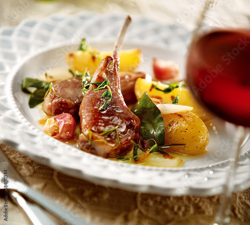 mesa de jantar com costeleta de cordeiro acompanhado de alho e batatas assadas e taça de vinho tinto  photo