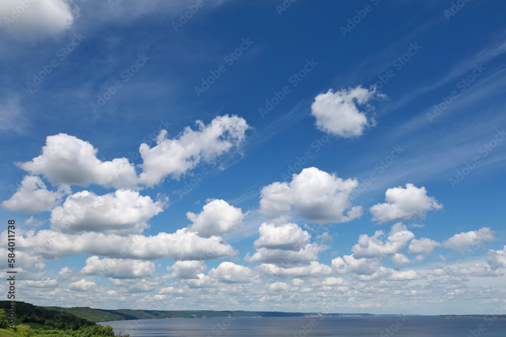 Blue sky with clouds. Spring or summer background. 
White clouds on the blue sky have a complex pattern.
