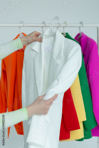 A woman's hands chooses clothes on a hanger on a white background.