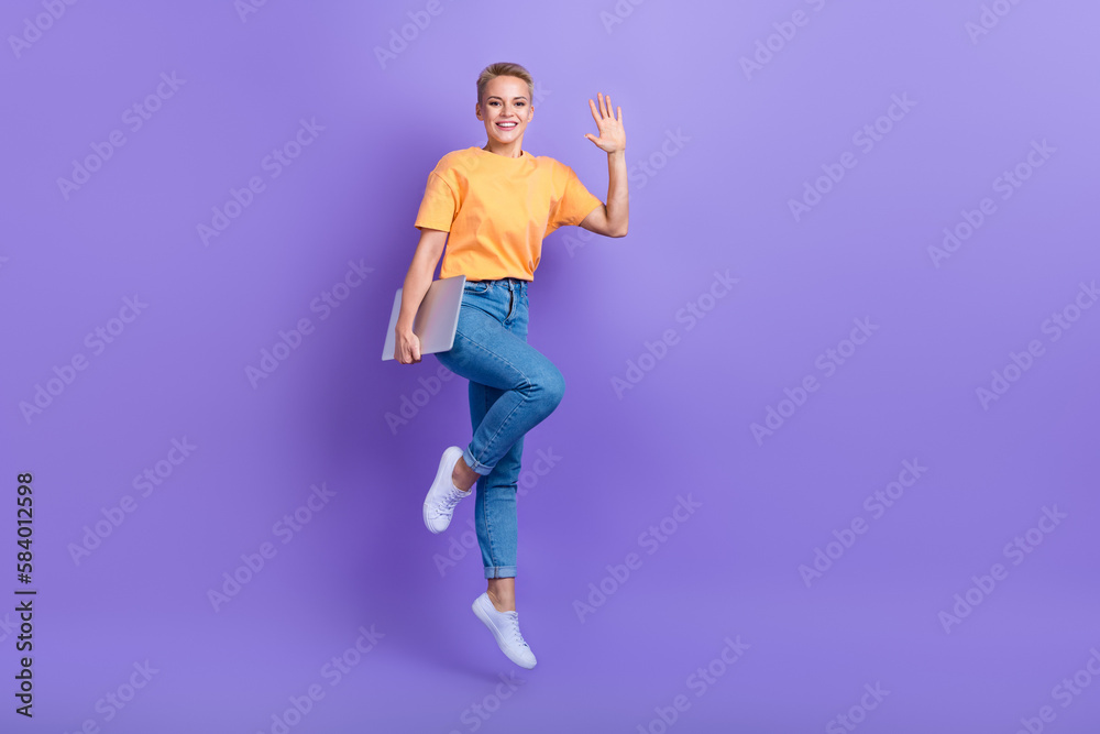 Full length photo of excited carefree person jumping hold netbook arm palm waving hi isolated on violet color background
