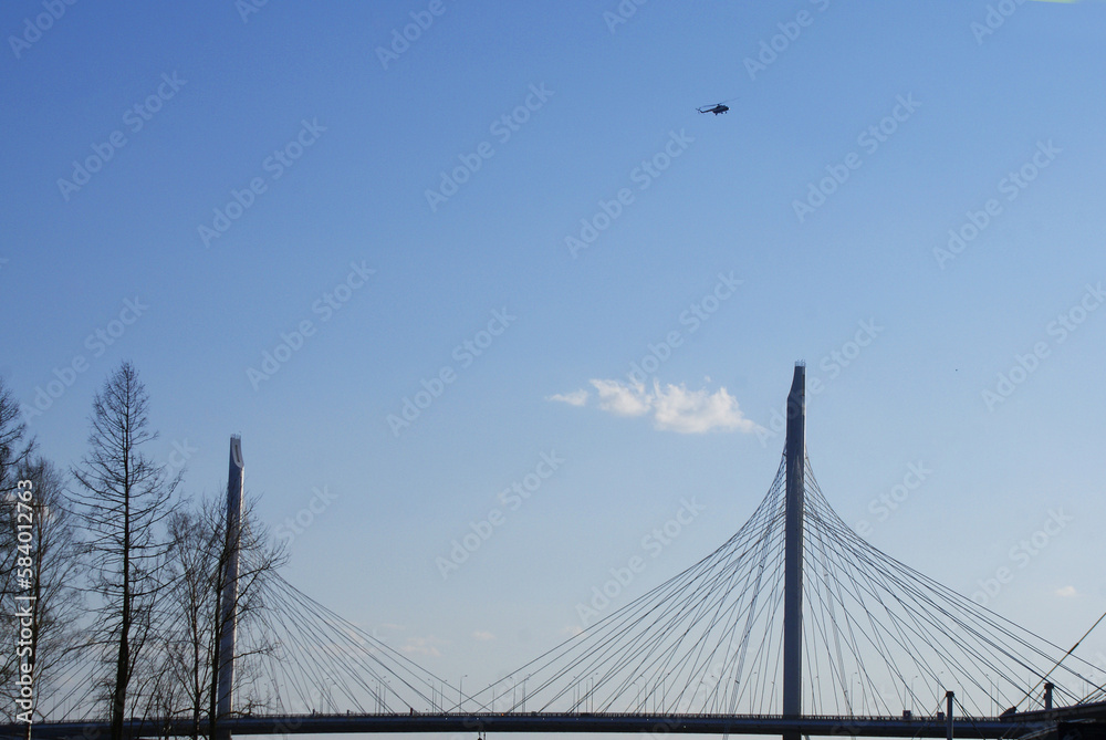 Obraz premium A military helicopter in the blue sky over the city.