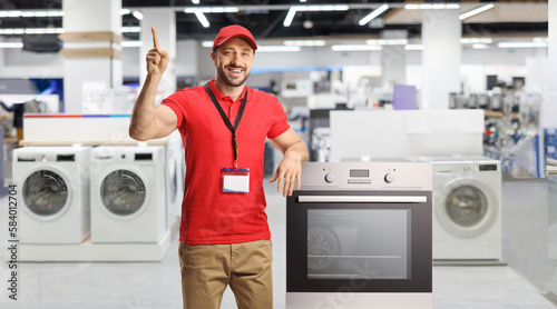 Salesman with electrical appliances smiling and pointing up in a store