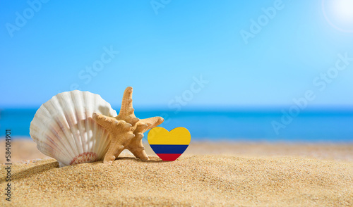 Beautiful beach in the Colombia. Flag of Colombia in the shape of a heart and shells on a sandy beach.