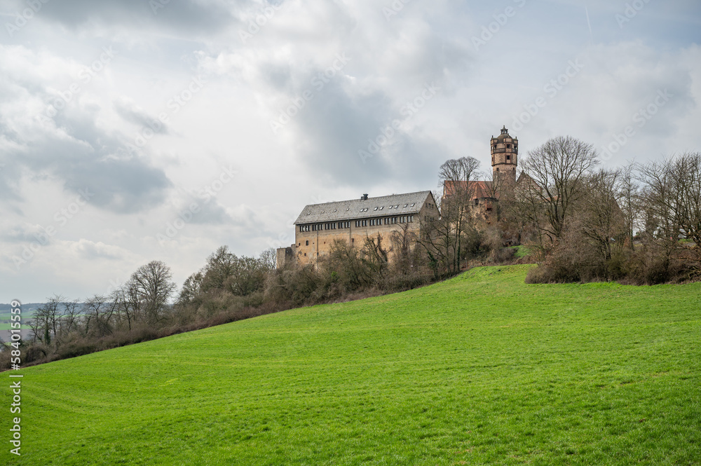 Beautiful Ronneburg Castle on top of a hill with meadow in front during cloudy day, view from the distance, Germany