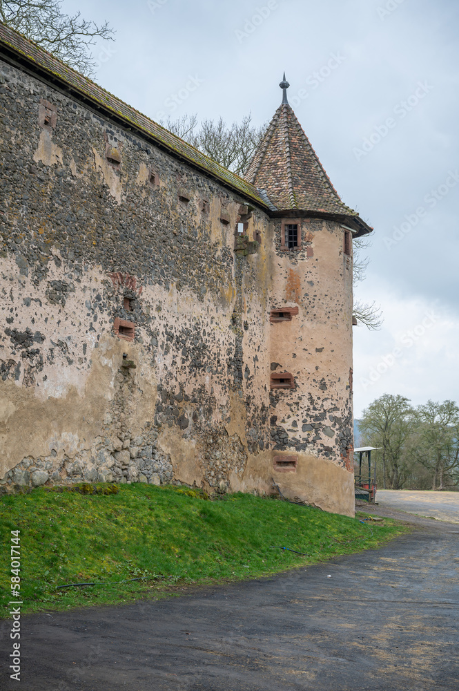 Walls with Tower of Ronneburg Castle with street in front during cloudy day, Germany, vertical shot