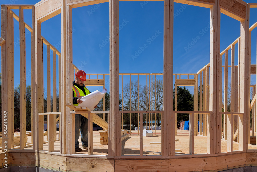 In construction process an architectural engineer checks quality of work on site using construction blueprints In construction process an architectural engineer checks quality of work on site using construction blueprints