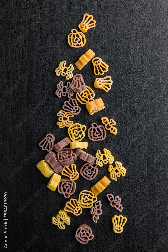 Pasta of various scary shapes. Uncooked halloween pasta on black table. Top view.