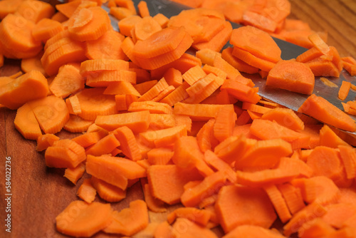 Cutting fresh carrot on a wooden cutting board close-up