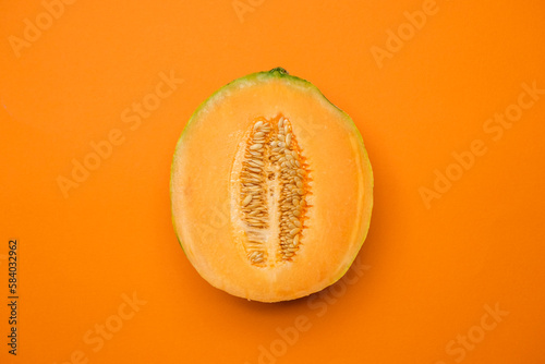 Half melon fresh organically grown on orange background. Sweet and juicy summer fruit. Cool minimal flat lay, copy space (ID: 584032962)