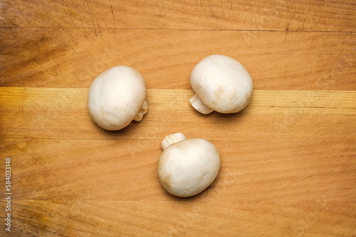 Fresh whole champignon mushrooms on a wooden background. Cool minimal flat lay, copy space.