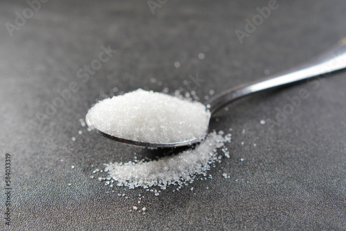 white sugar on a silver spoon on table 