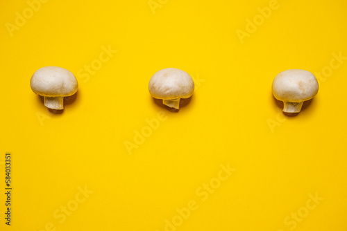 Fresh whole champignon mushrooms on a yellow background. Cool minimal flat lay, copy space. (ID: 584033351)