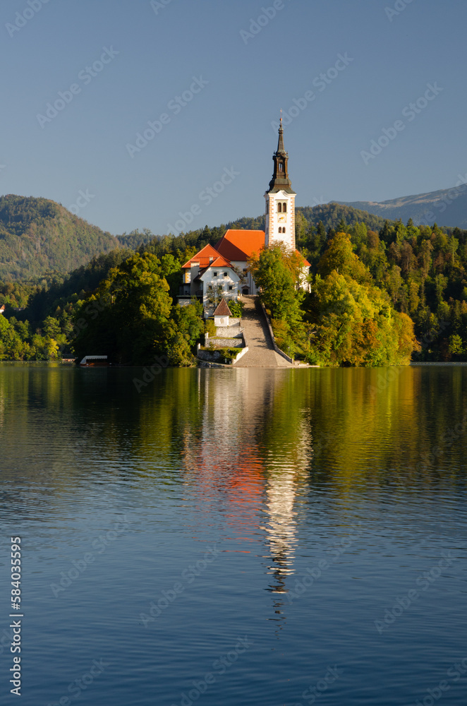 Front view of the iconic church on the island in Bled during september. Colorful autumn in Slovenia.
