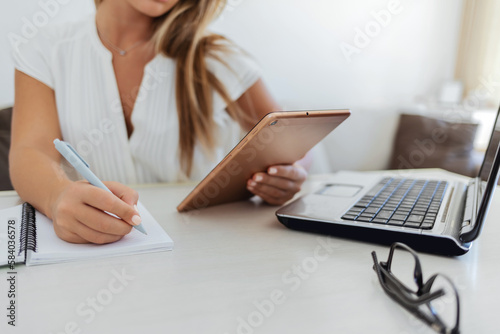 Shot of a businesswoman using a digital tablet at her desk in a modern office. Cropped shot of a businesswoman using a laptop and digital tablet at her desk in a home office.