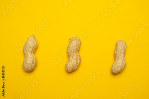 Whole peanuts in shell on a yellow background. Protein and healthy dried fruit. Cool minimal flat lay, copy space 