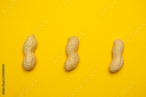 Whole peanuts in shell on a yellow background. Protein and healthy dried fruit. Cool minimal flat lay, copy space  (ID: 584040314)