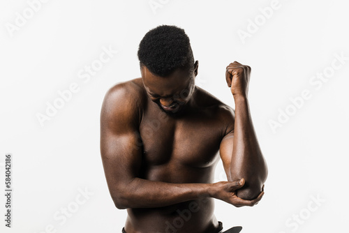 Sport traumatology. Elbow injury of muscular african american man on white background. African american man with pain and bruise in his arm due to an accident.