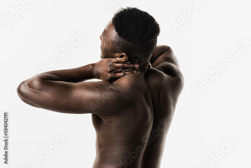 Cervical spine osteochondrosis is radicular syndromes of african american man. Muscular shirtless african man feel spine and neck pain because of spinal nerves compression on white background.