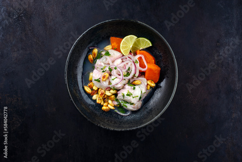 Traditional Peruvian gourmet ceviche sea bass filet piece with sweet potatoes and cancha marinated and served in lime sauce as top view in a modern design bowl with copy space photo