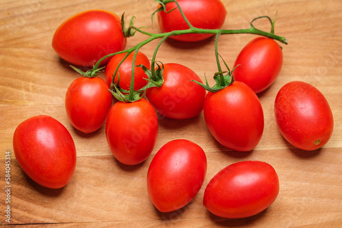 San marzano DOP cherry tomato branch with ripe, little tomatoes on a wooden cutting board.