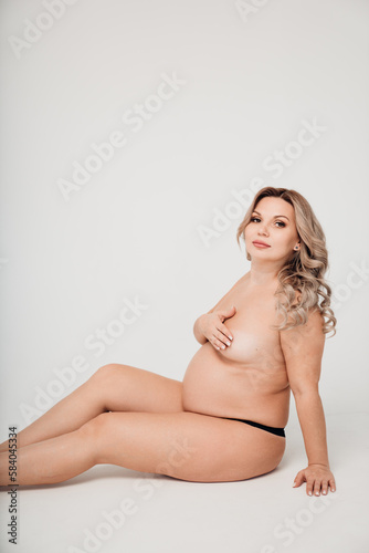 a naked pregnant against the background of a white cyclorama in a photo studio.  © andrey