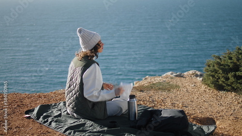 Girl resting ocean cliff picnic on spring vacation. Carefree tourist admire view