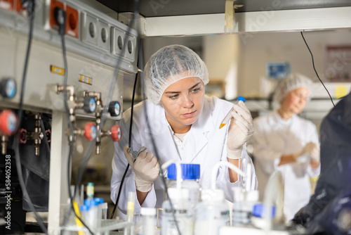 Portrait of young woman technical expert provide during work at science research laboratory, holding test tube and looking at it