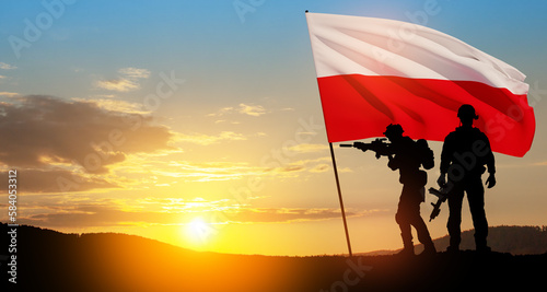 Silhouettes of soldiers with national flag on background of sunset. Polish Armed Forces.