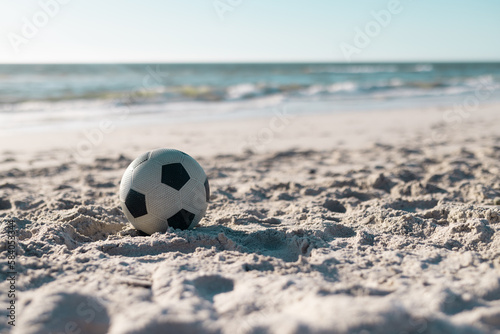 Soccer ball on sandy beach with scenic view of beautiful sea and clear sky in the background © WavebreakMediaMicro