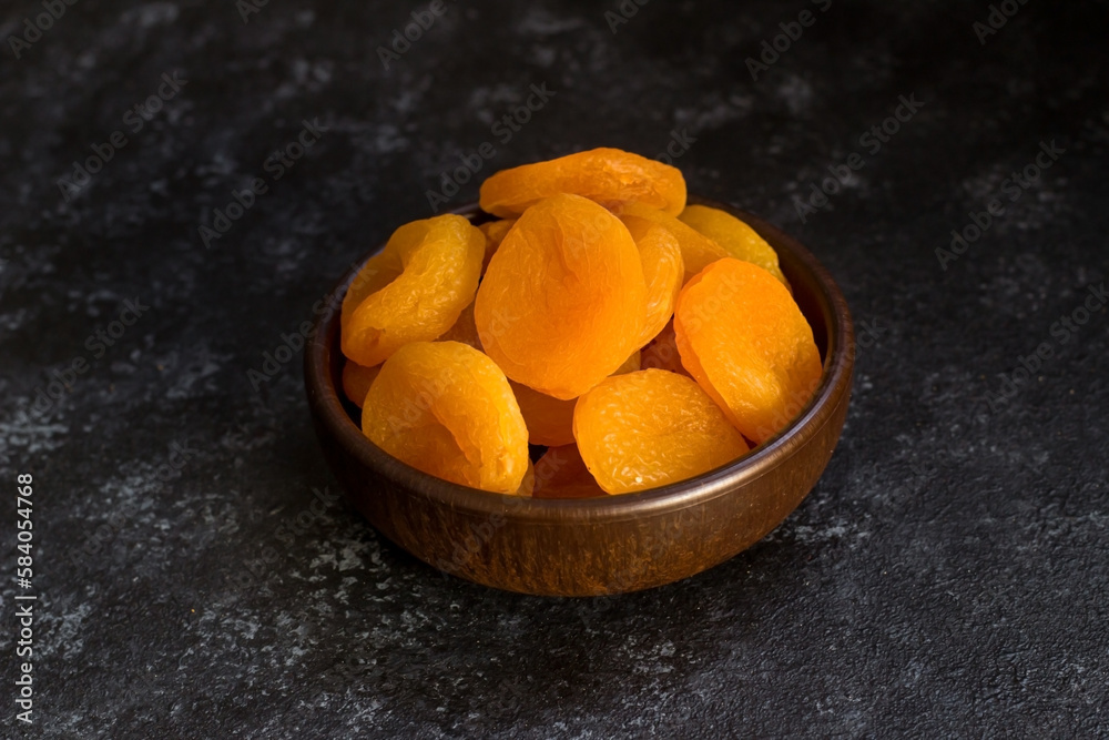 Dried apricot designed on wooden bowl on black surface.Conceptual image Dried apricot designed on wooden bowl on black surface.Conceptual image