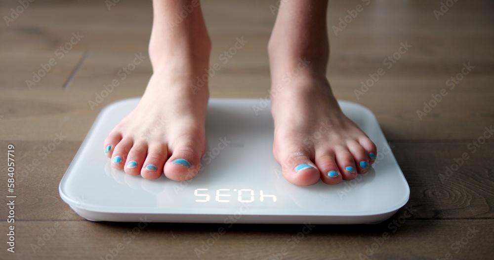 Φωτογραφία Young female teen stands barefoot on white scales to measure weight