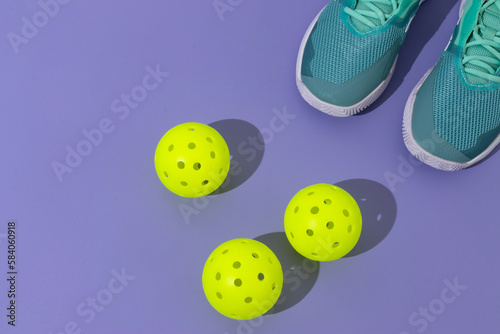 pickle ball balls and tennis shoes on lavender  background with space for text