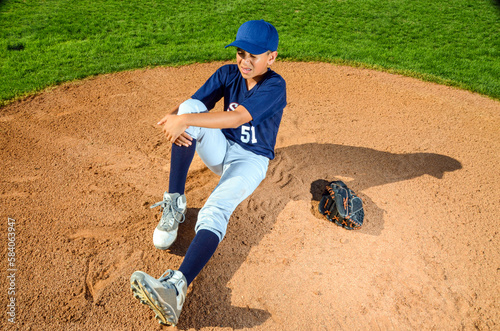 Young preteen boy baseball player injured on the field