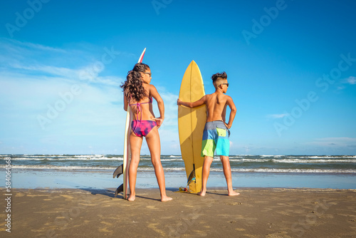 Photography Preteens standing on sunny beach holding surfboards