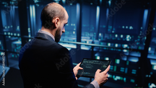 IT support specialist working with hosting server using tablet in professional data center, planning web digitalization. Male database admin inspecting system hardware in networking industry. © DC Studio