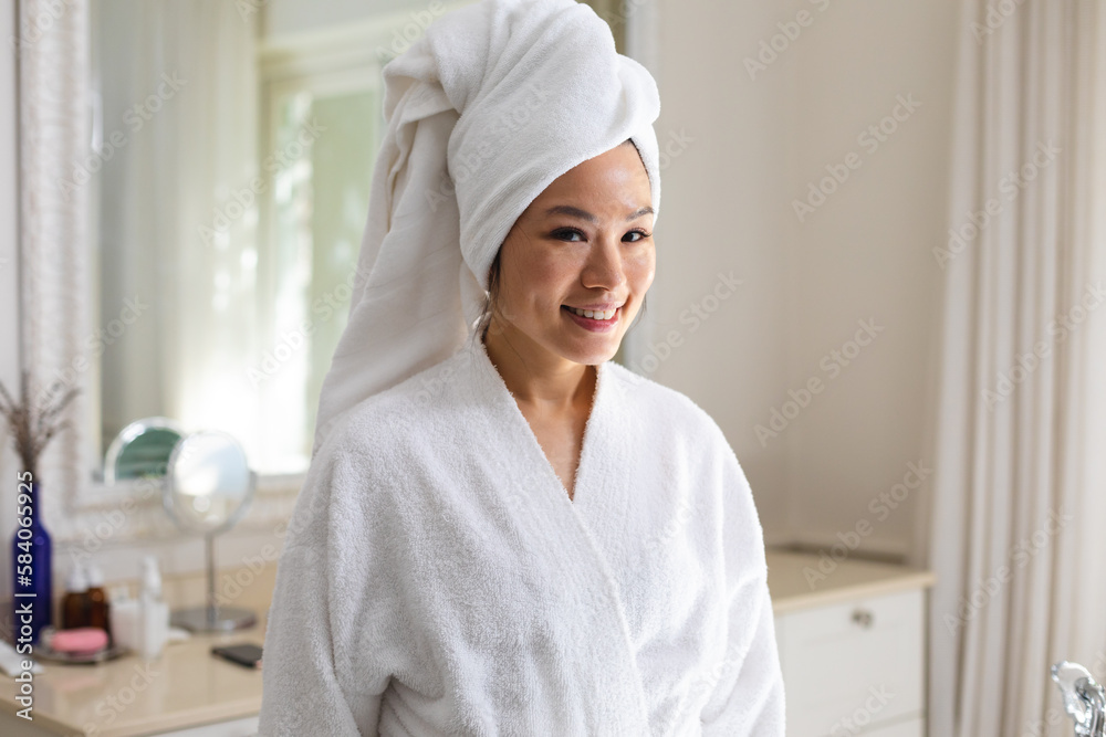 Portrait of happy asian woman wearing bathrobe and towel on head smiling in bathroom Portrait of happy asian woman wearing bathrobe and towel on head smiling in bathroom