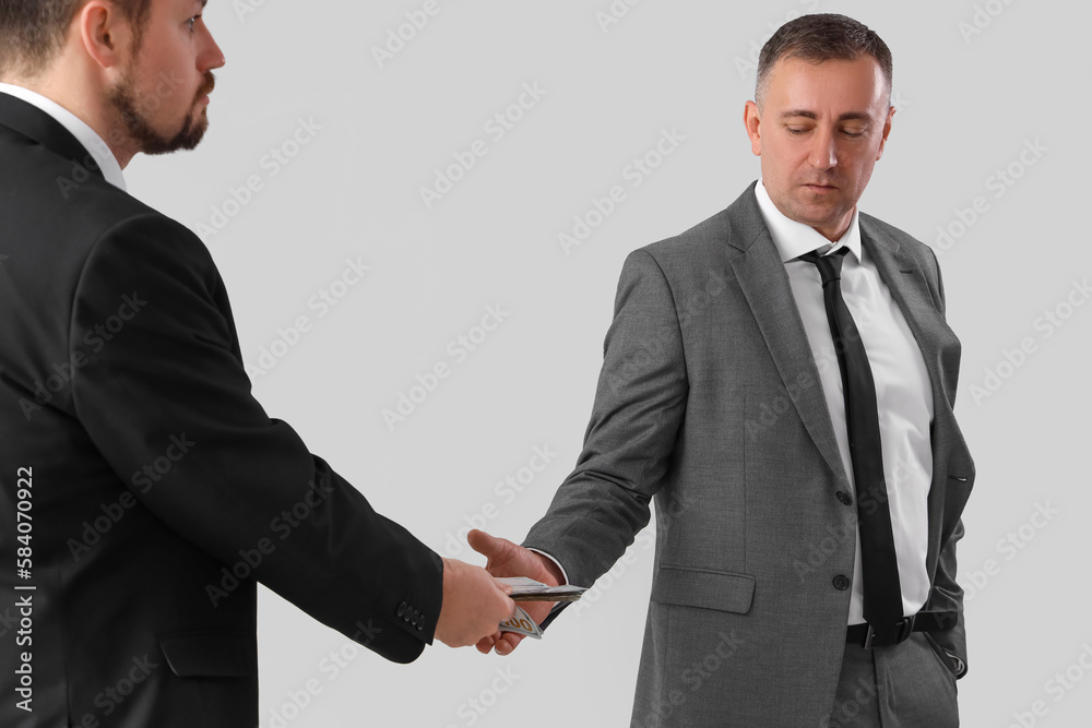 Businessman taking bribe from man on grey background Businessman taking bribe from man on grey background