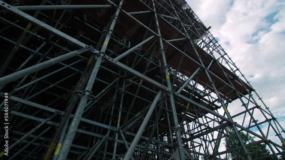 Scaffolds and steel fittings around road bridge support tower silhouette at back sunlight. Building site of highway construction Scaffolds and steel fittings around road bridge support tower silhouette at back sunlight. Building site of highway construction