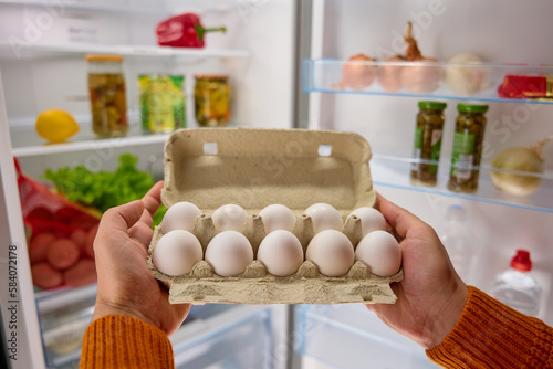 man hands take white chicken eggs from the fridge
