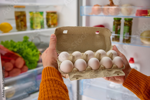 man hands take white chicken eggs from the fridge