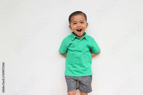 Portrait of a happy little Asian boy looking at camera while shouting on the white background