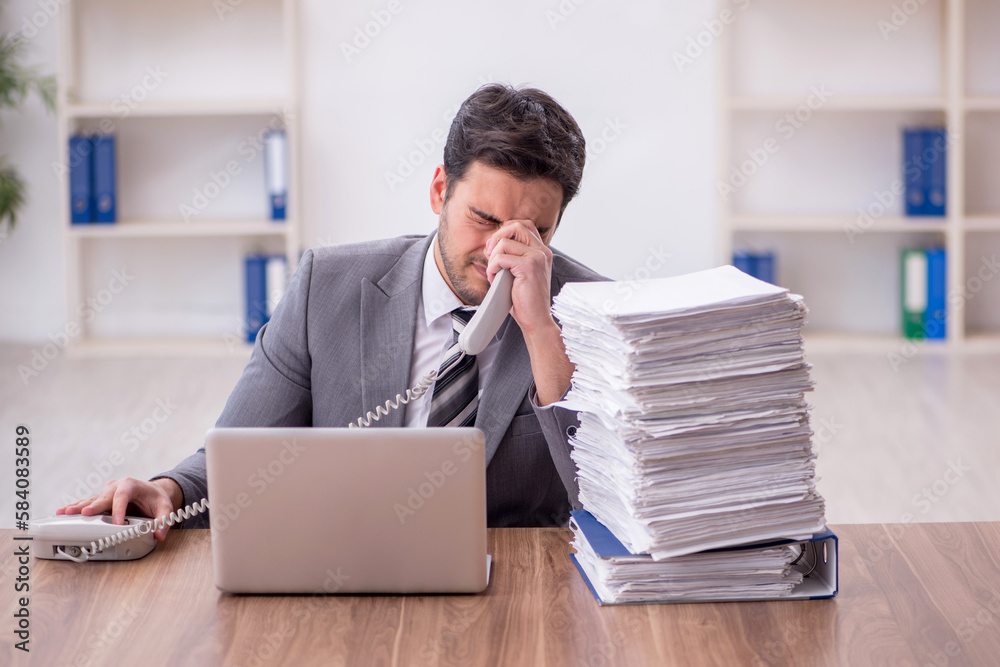 Young male employee and too much work in the office Young male employee and too much work in the office