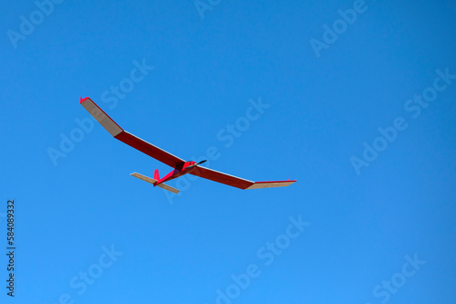 A radio controlled powered model glider soars against a blue sky background.