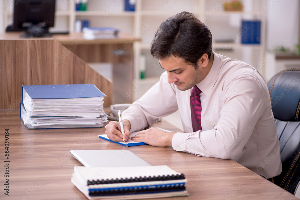 Young male employee and too much work in the office Young male employee and too much work in the office