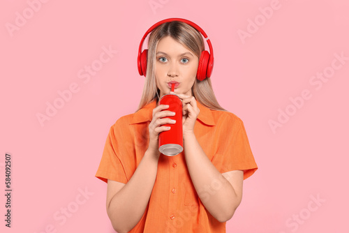 Beautiful woman drinking from red beverage can on pink background