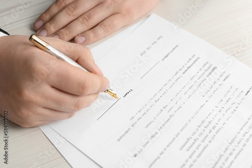 Notary signing document at wooden table, closeup