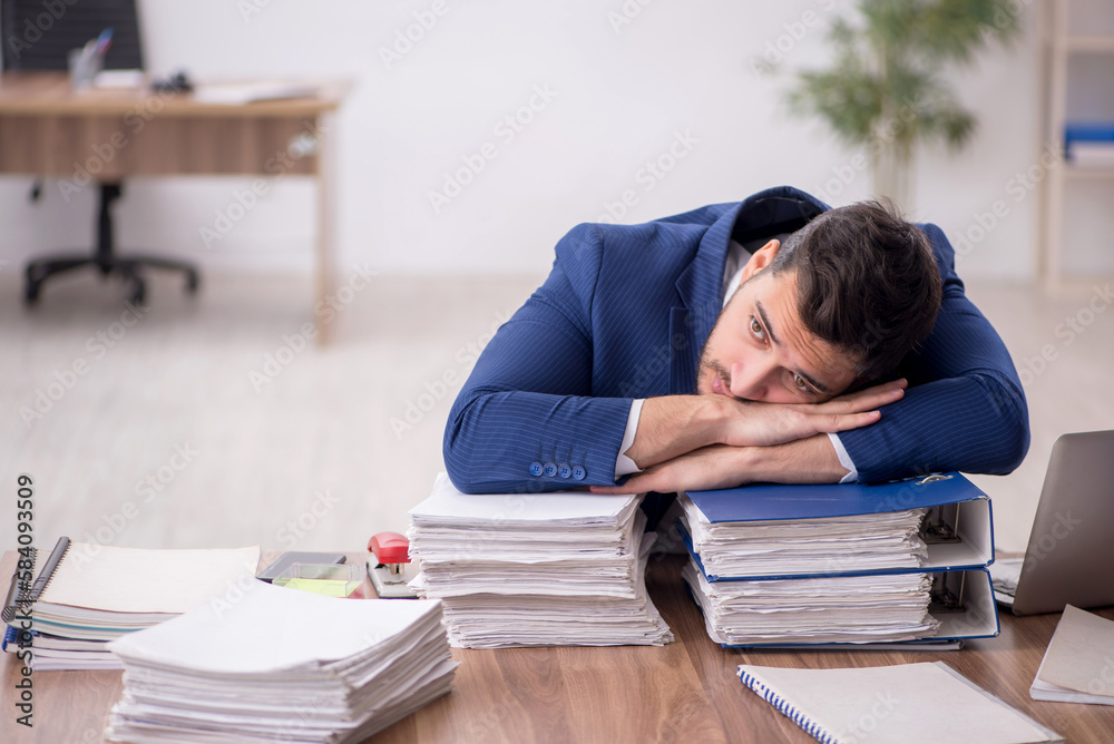 Young male employee and too much work in the office Young male employee and too much work in the office