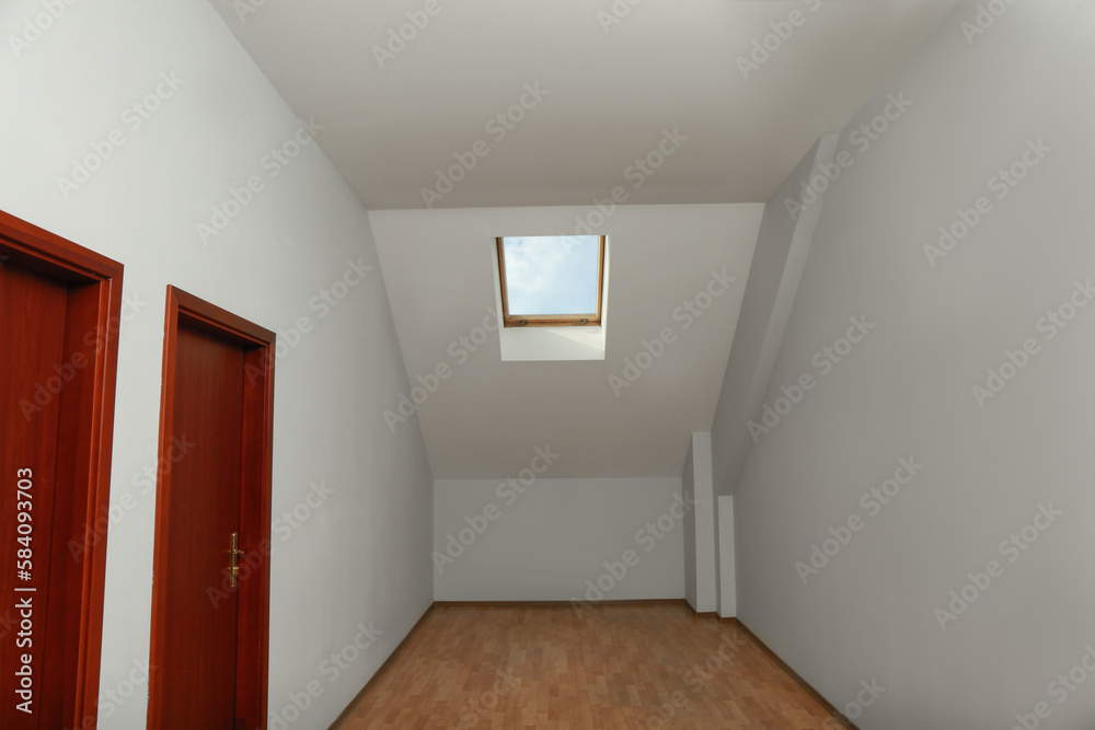 Light spacious attic room with roof window on slanted ceiling Light spacious attic room with roof window on slanted ceiling
