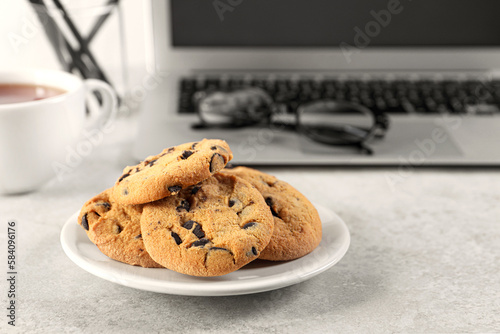 Chocolate chip cookies on light gray table at workplace